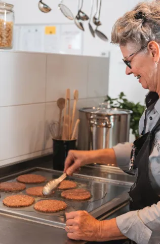 Cateringmedewerker bakt hamburgers op bakplaat