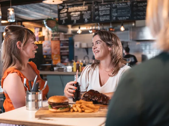 Twee vrouwen eten hamburger en spareribs in restaurant